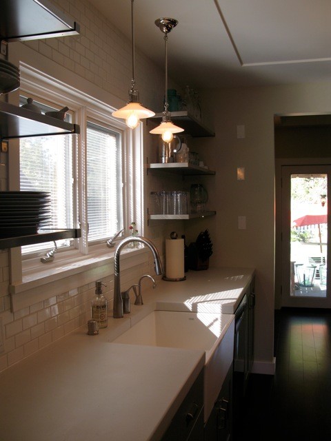 Mid-sized transitional galley dark wood floor enclosed kitchen photo in Seattle with a farmhouse sink, shaker cabinets, blue cabinets, quartz countertops, white backsplash, ceramic backsplash, black appliances and an island