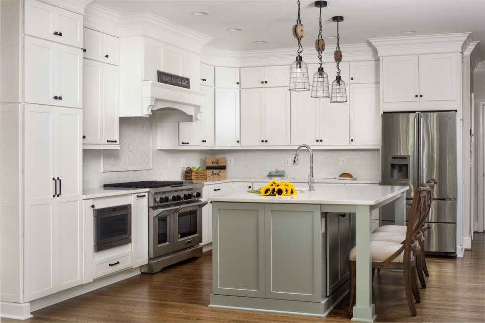 Photo of a large country l-shaped eat-in kitchen in Atlanta with a farmhouse sink, shaker cabinets, white cabinets, quartz benchtops, white splashback, stainless steel appliances, medium hardwood floors, with island and brown floor.