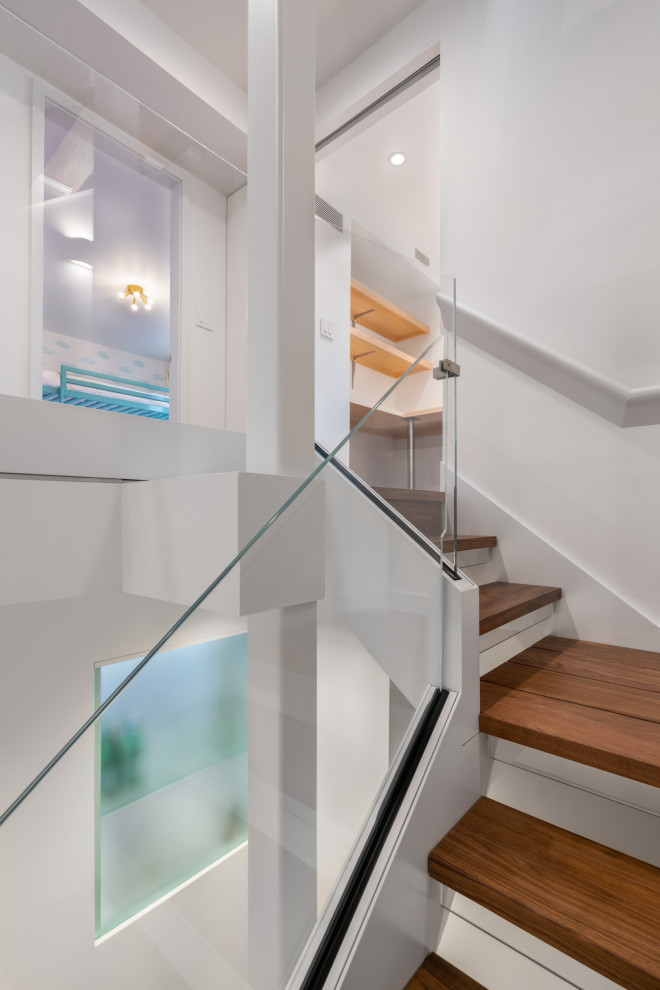 Imagen de escalera suspendida moderna pequeña con escalones de madera, contrahuellas de vidrio y barandilla de vidrio