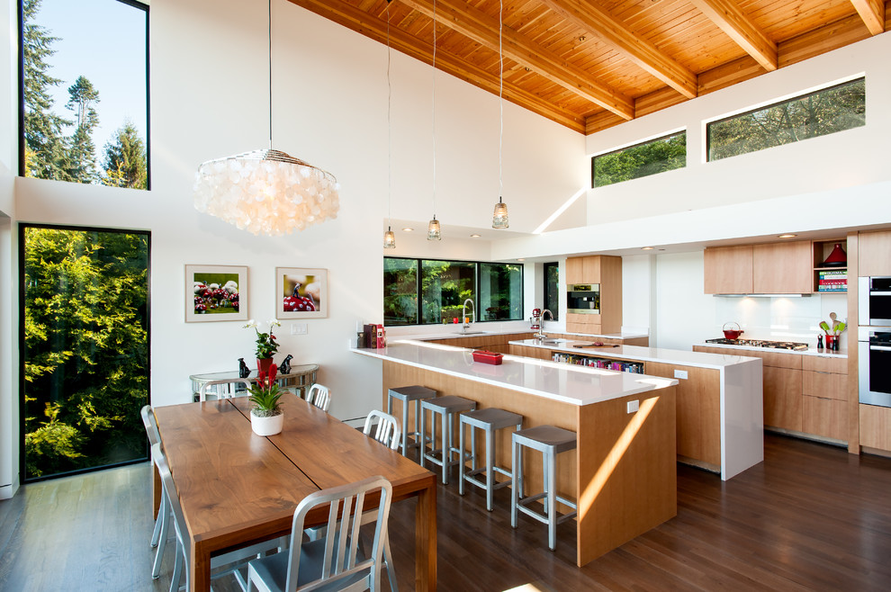 Large contemporary u-shaped eat-in kitchen in Seattle with light wood cabinets, white splashback, stainless steel appliances and multiple islands.