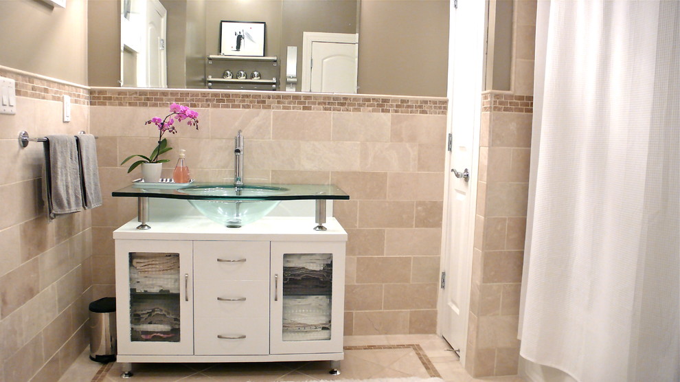 Photo of a mid-sized modern master bathroom in New York with white cabinets, a drop-in tub, a one-piece toilet, beige tile, porcelain tile, brown walls, porcelain floors, an integrated sink and glass benchtops.
