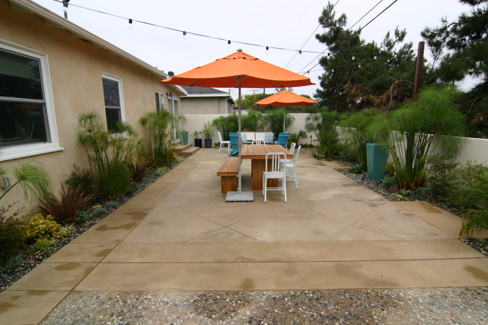 This is an example of a small beach style backyard patio in Los Angeles with a fire feature and concrete slab.
