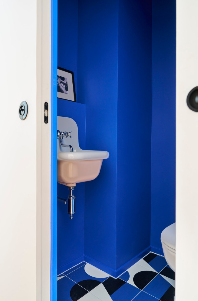 Cette photo montre un WC et toilettes éclectique avec un mur bleu, un lavabo suspendu et un sol multicolore.