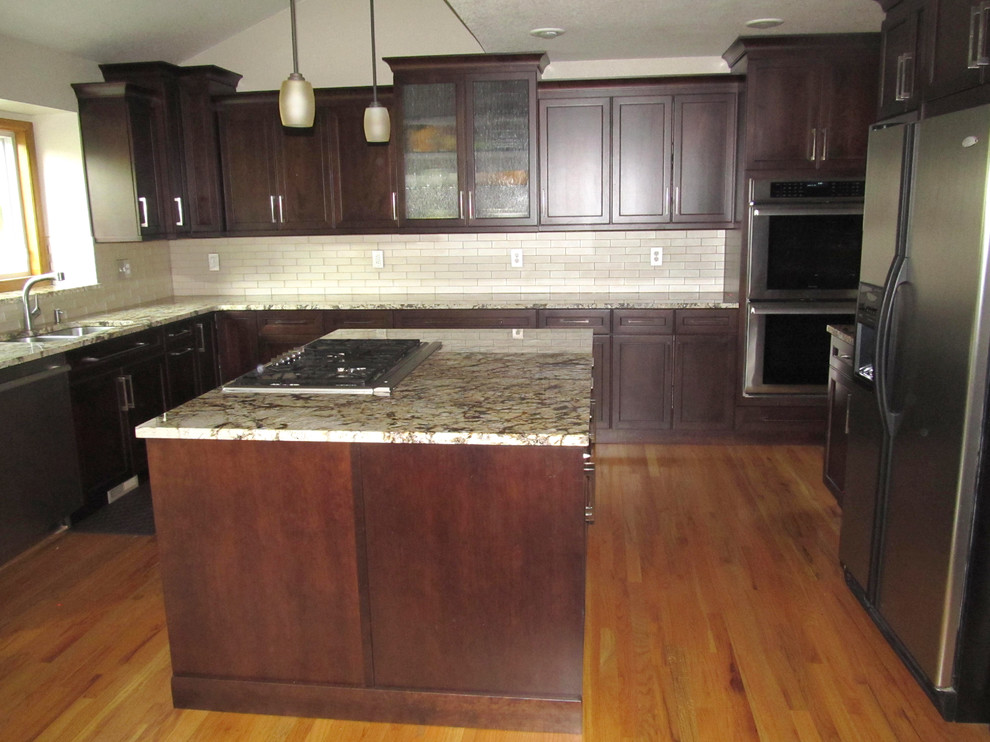 This is an example of a large transitional u-shaped separate kitchen in Denver with an undermount sink, shaker cabinets, dark wood cabinets, granite benchtops, white splashback, subway tile splashback, stainless steel appliances, medium hardwood floors and with island.