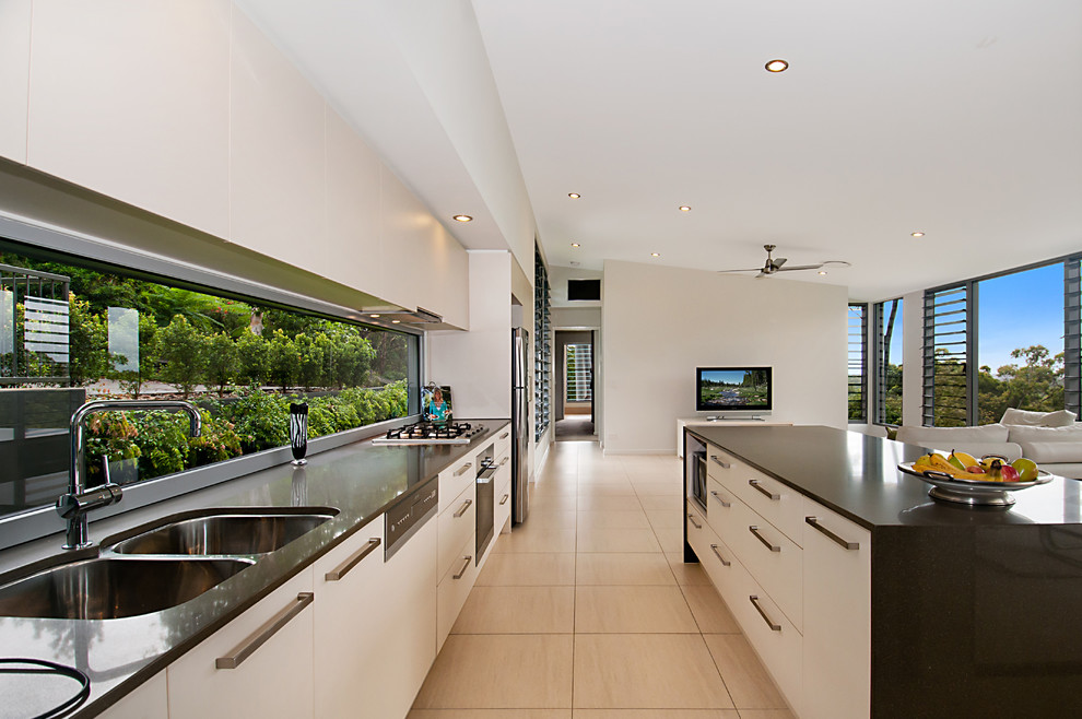 Contemporary galley kitchen in Brisbane with an undermount sink, quartz benchtops, glass sheet splashback, porcelain floors and with island.