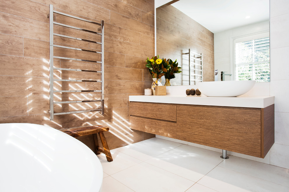 Design ideas for a large traditional master bathroom in Sydney with a freestanding tub, ceramic tile, beige walls, ceramic floors, a vessel sink, flat-panel cabinets, medium wood cabinets, brown tile, engineered quartz benchtops and white floor.