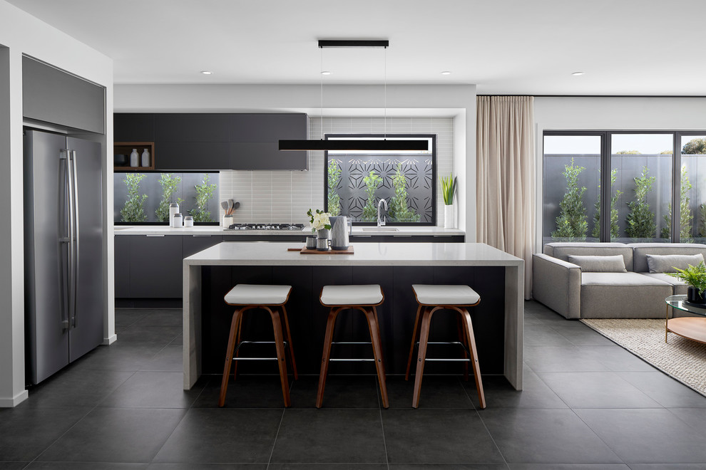 Photo of a contemporary l-shaped open plan kitchen in Melbourne with an undermount sink, flat-panel cabinets, grey cabinets, white splashback, mosaic tile splashback, stainless steel appliances, with island, grey floor and white benchtop.