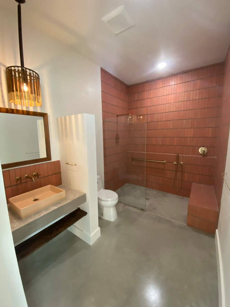 На фото: ванная комната в стиле фьюжн с открытым душем, унитазом-моноблоком, красной плиткой, терракотовой плиткой, бетонным полом, столешницей из бетона, серым полом, открытым душем, сиденьем для душа, тумбой под одну раковину и встроенной тумбой
