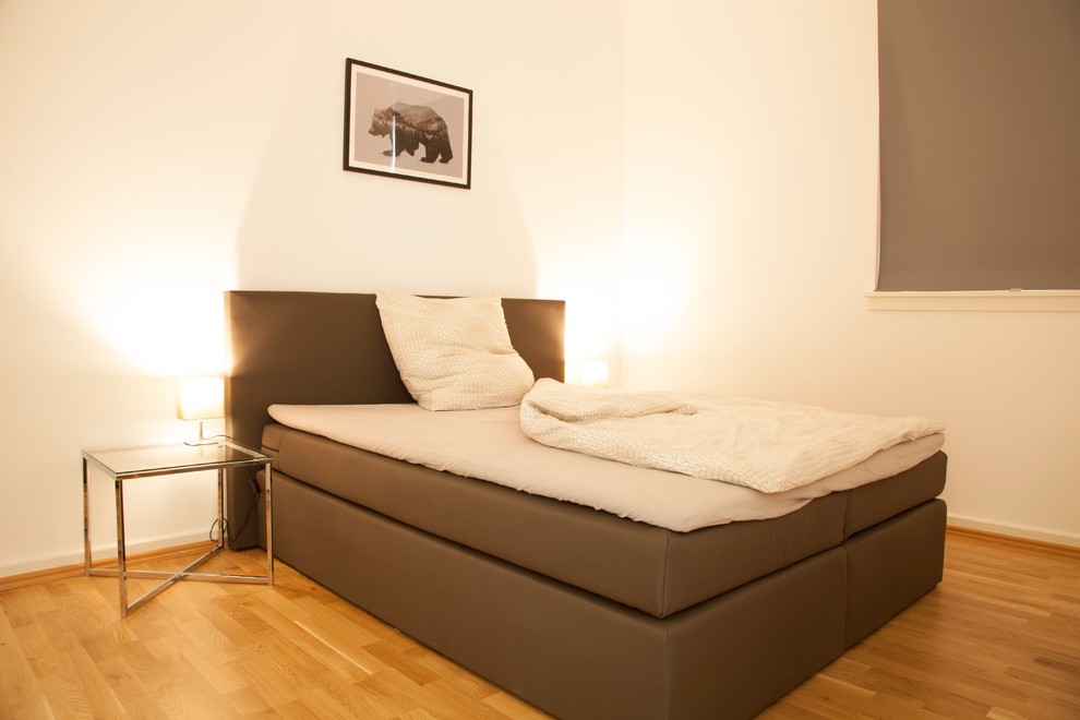 Small contemporary master bedroom in Frankfurt with white walls and light hardwood floors.