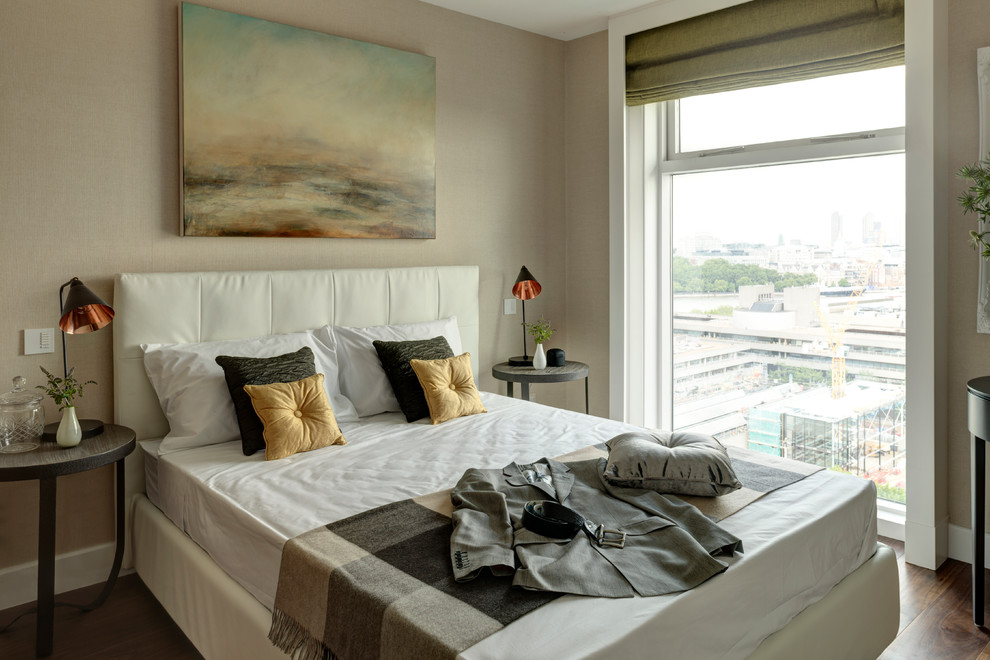 This is an example of a contemporary bedroom in London with beige walls and medium hardwood floors.