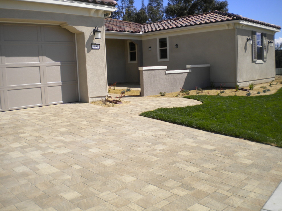 Photo of a mid-sized traditional front yard partial sun driveway in Los Angeles with concrete pavers.