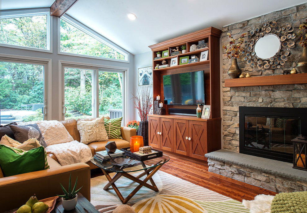 Inspiration for a large transitional open concept family room in New York with medium hardwood floors, a standard fireplace, a stone fireplace surround, a built-in media wall, grey walls and vaulted.