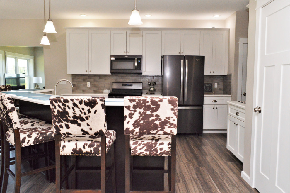 Open concept kitchen - mid-sized transitional single-wall open concept kitchen idea with a drop-in sink, shaker cabinets, white cabinets, quartzite countertops, beige backsplash, stainless steel appliances, an island and white countertops