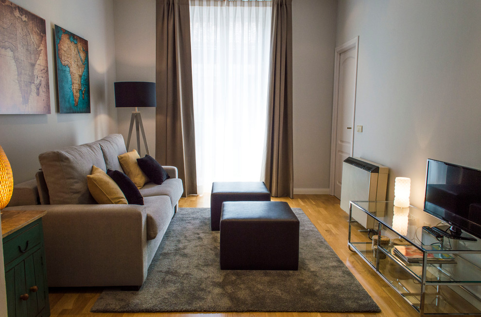 Foto de salón cerrado clásico renovado de tamaño medio sin chimenea con paredes beige, suelo de madera en tonos medios y pared multimedia