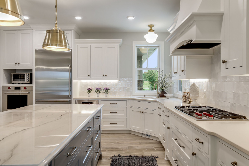 Design ideas for a large u-shaped eat-in kitchen in Minneapolis with an undermount sink, beaded inset cabinets, white cabinets, quartzite benchtops, white splashback, ceramic splashback, stainless steel appliances, light hardwood floors, with island and beige benchtop.