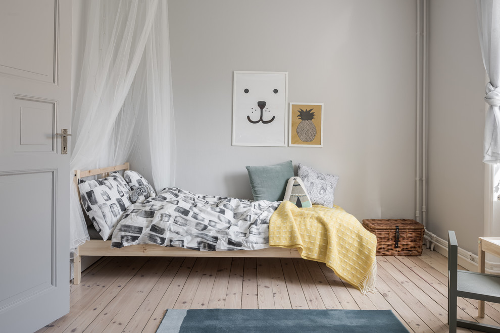 Idéer för mellanstora minimalistiska könsneutrala barnrum kombinerat med sovrum och för 4-10-åringar, med grå väggar och ljust trägolv