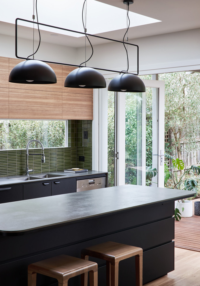 Exempel på ett mellanstort modernt grå grått kök, med en undermonterad diskho, släta luckor, svarta skåp, laminatbänkskiva, grönt stänkskydd, stänkskydd i porslinskakel, rostfria vitvaror, ljust trägolv och en köksö