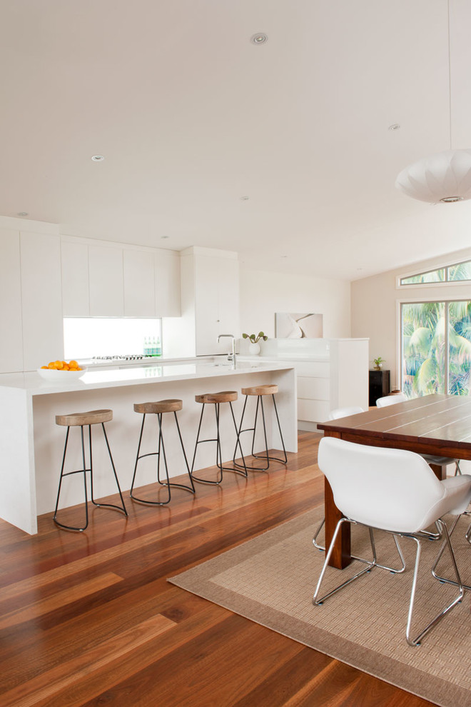 This is an example of a mid-sized galley eat-in kitchen in Sydney with flat-panel cabinets, white cabinets and with island.