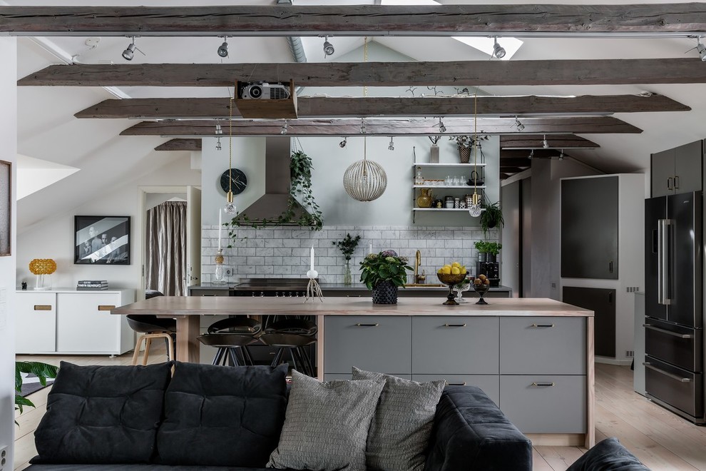 Industrial kitchen in Stockholm with grey cabinets, with island, wood benchtops, grey splashback, marble splashback, medium hardwood floors and beige floor.