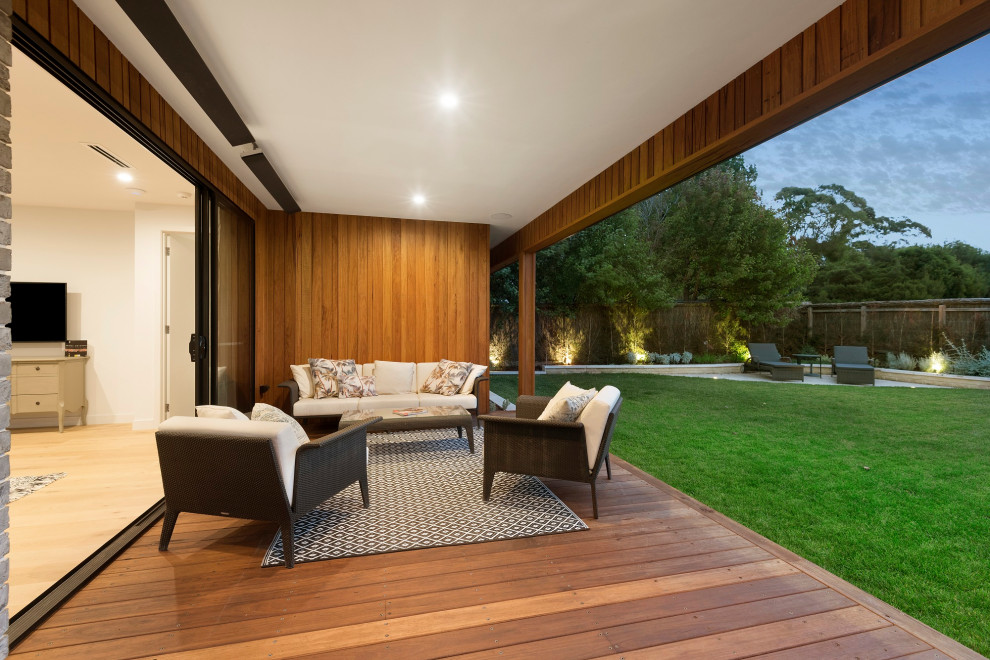 Inspiration for a mid-sized modern backyard deck in Melbourne with with privacy feature and a roof extension.