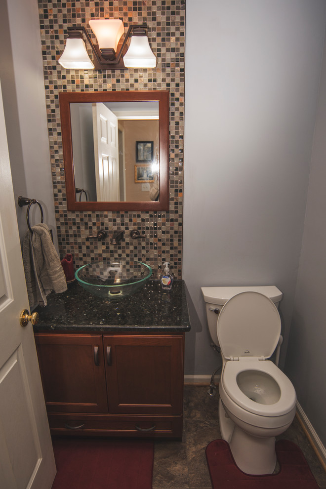 Design ideas for a small powder room in New York with recessed-panel cabinets, dark wood cabinets, a wall-mount toilet, brown tile and blue walls.