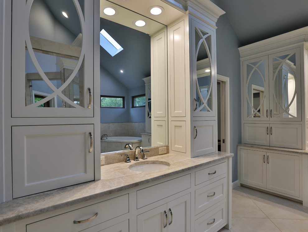 This is an example of a bathroom in Dallas with raised-panel cabinets, a drop-in tub, a double shower, a one-piece toilet, blue tile, porcelain tile, blue walls, porcelain floors, an undermount sink, granite benchtops, beige floor, an open shower and blue benchtops.