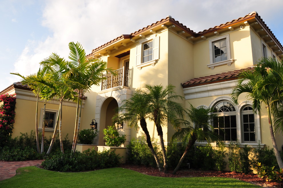 Design ideas for a large mediterranean two-storey stucco yellow exterior in Miami.