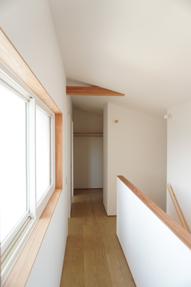Foto på en liten minimalistisk hall, med vita väggar, plywoodgolv och beiget golv