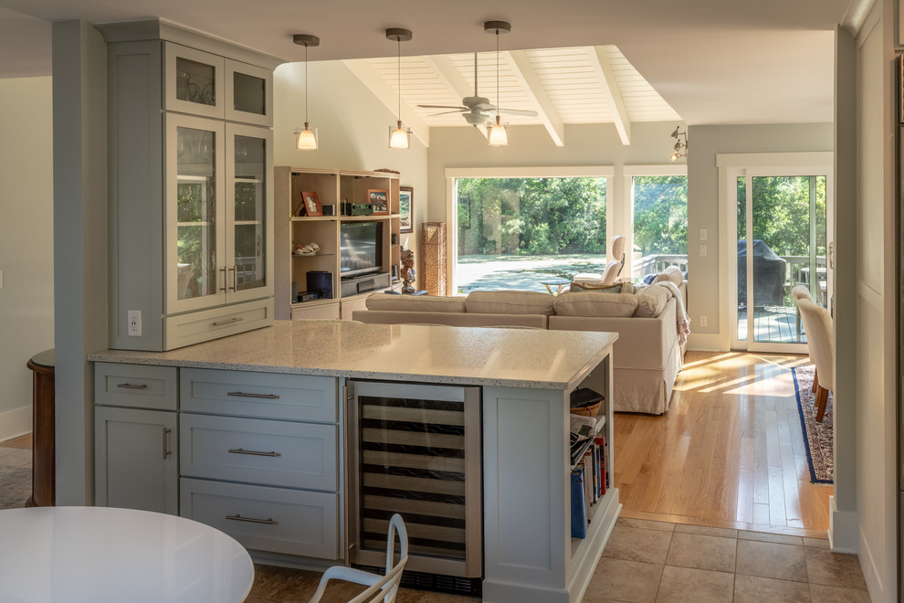 Design ideas for a beach style u-shaped kitchen in Charleston with a farmhouse sink, recessed-panel cabinets, white cabinets, recycled glass benchtops, grey splashback, glass tile splashback and stainless steel appliances.