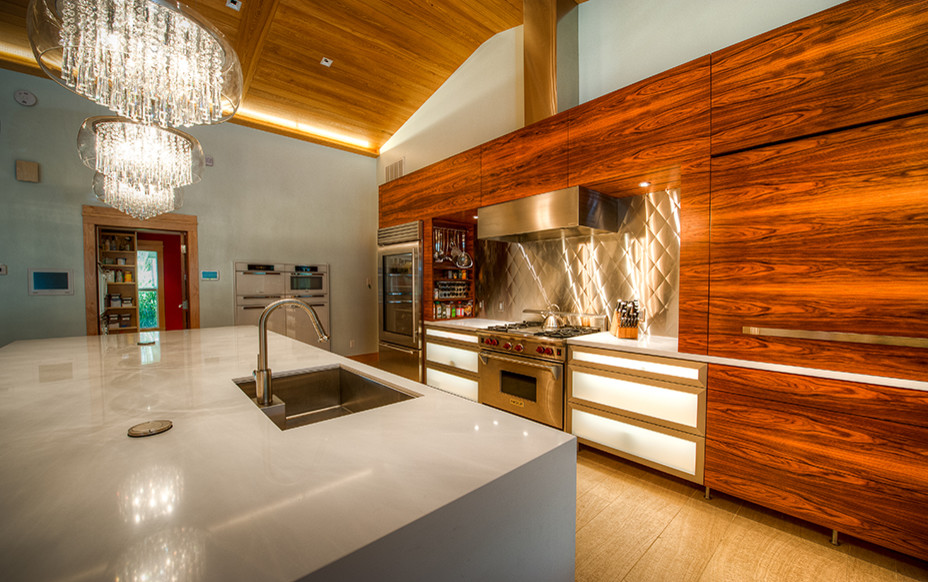 Mid-sized contemporary l-shaped eat-in kitchen in Miami with an undermount sink, flat-panel cabinets, medium wood cabinets, quartz benchtops, metallic splashback, stainless steel appliances, light hardwood floors, with island and beige floor.