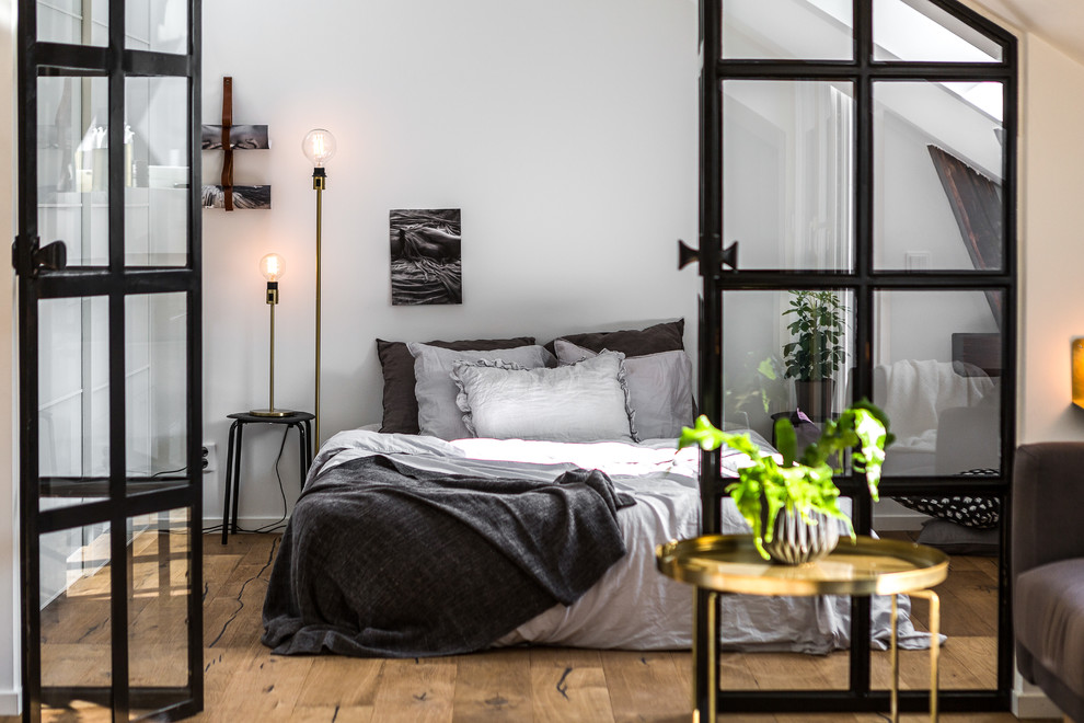 Photo of a large scandinavian master bedroom in Stockholm with white walls and light hardwood floors.