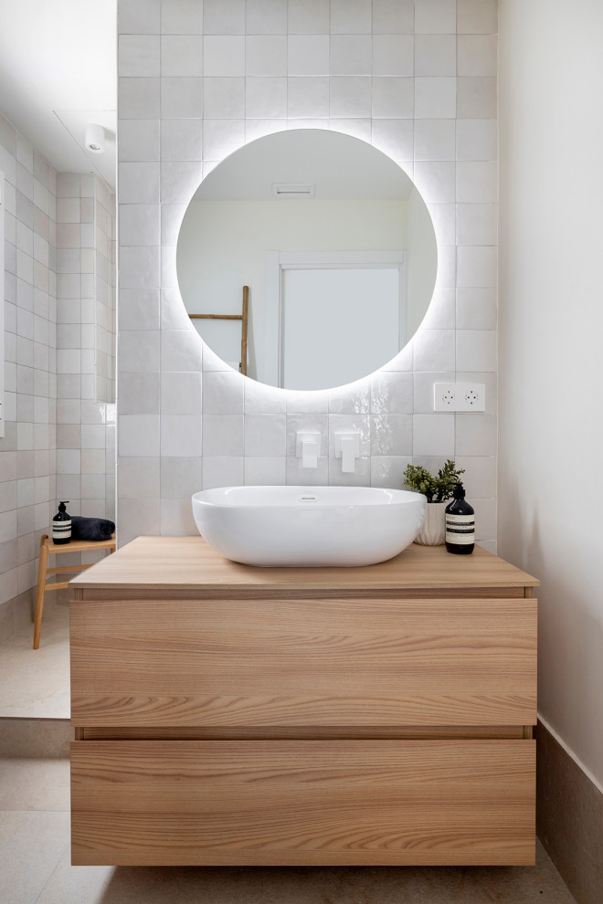 Idéer för ett mellanstort minimalistiskt vit en-suite badrum, med släta luckor, skåp i mellenmörkt trä, en dusch i en alkov, vit kakel, keramikplattor, vita väggar, klinkergolv i keramik, ett fristående handfat, träbänkskiva, beiget golv och med dusch som är öppen