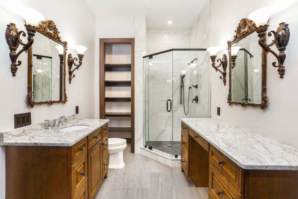 Inspiration for a mid-sized contemporary master bathroom in New York with raised-panel cabinets, medium wood cabinets, a corner shower, a two-piece toilet, white tile, white walls, porcelain floors, an undermount sink, granite benchtops, grey floor, a hinged shower door, grey benchtops, a single vanity and a built-in vanity.