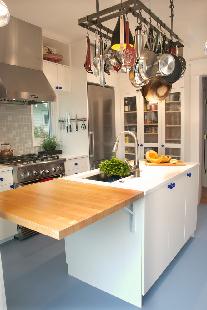 This is an example of a small transitional single-wall eat-in kitchen in Seattle with flat-panel cabinets, white cabinets, stainless steel appliances, with island, grey floor and white benchtop.