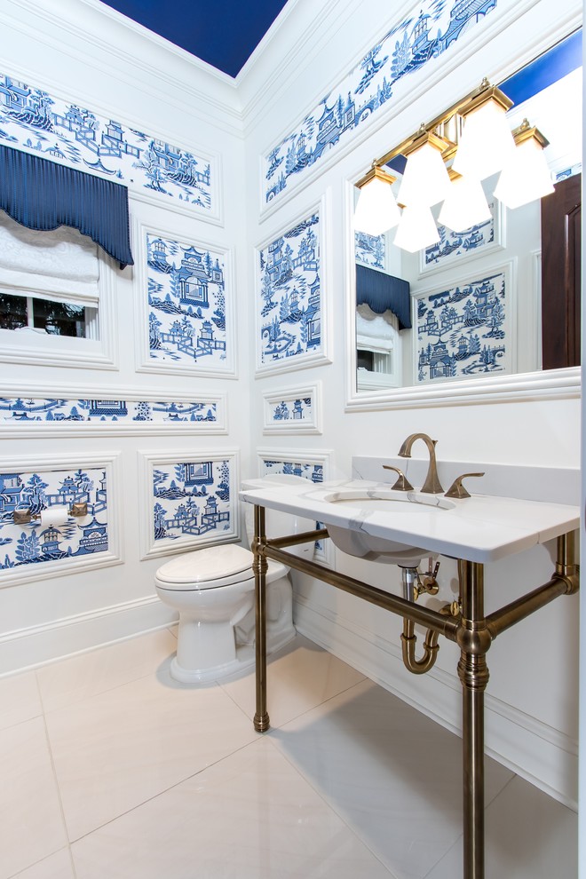 Photo of a mid-sized traditional powder room in Cleveland with a two-piece toilet, white walls, ceramic floors, an undermount sink, marble benchtops, beige floor and white benchtops.