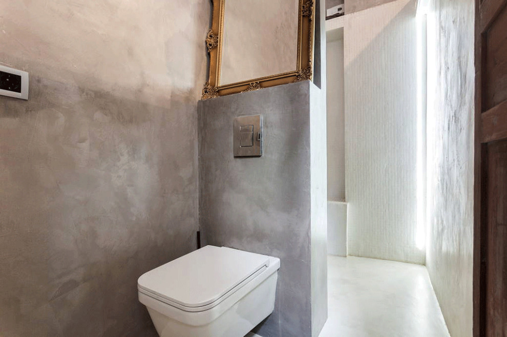 Idéer för att renovera ett litet eklektiskt vit vitt toalett, med öppna hyllor, vita skåp, en vägghängd toalettstol, vit kakel, keramikplattor, grå väggar, betonggolv, ett nedsänkt handfat, kaklad bänkskiva och vitt golv