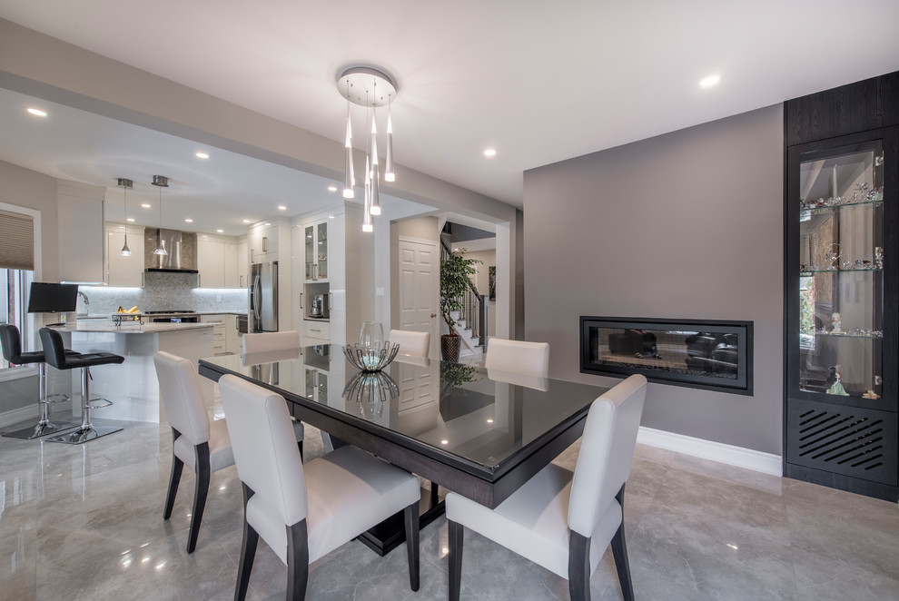 Photo of a mid-sized contemporary open plan dining in Toronto with grey walls, a metal fireplace surround, grey floor, a two-sided fireplace and marble floors.