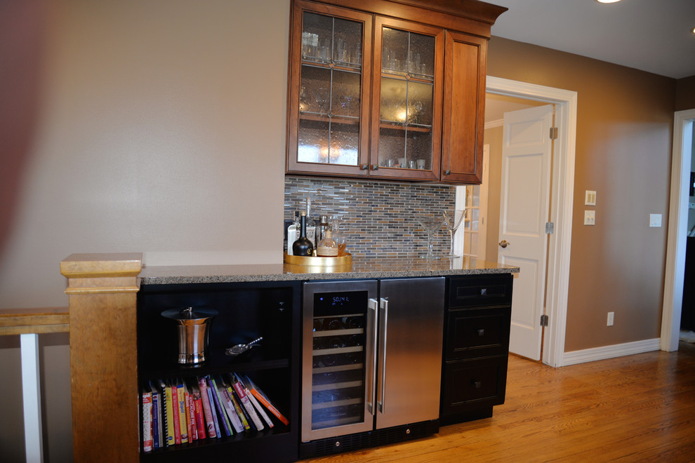 Example of a mid-sized transitional u-shaped light wood floor open concept kitchen design in Grand Rapids with an undermount sink, recessed-panel cabinets, black cabinets, quartzite countertops, multicolored backsplash, glass tile backsplash, stainless steel appliances and an island