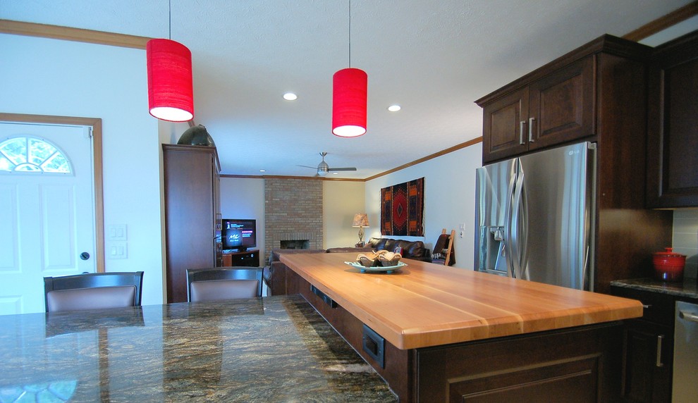 Large transitional l-shaped eat-in kitchen photo in Columbus with an undermount sink, raised-panel cabinets, dark wood cabinets, granite countertops, gray backsplash, ceramic backsplash, stainless steel appliances and an island