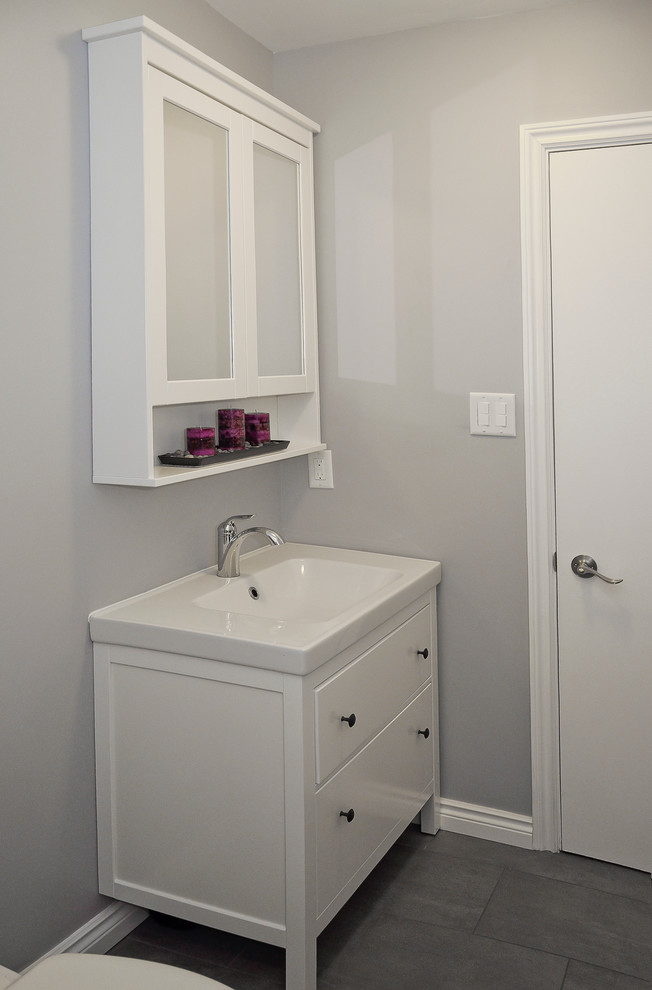 Example of a small transitional master gray tile and porcelain tile porcelain tile home design design in Ottawa with shaker cabinets, white cabinets, a two-piece toilet, gray walls, an integrated sink and solid surface countertops