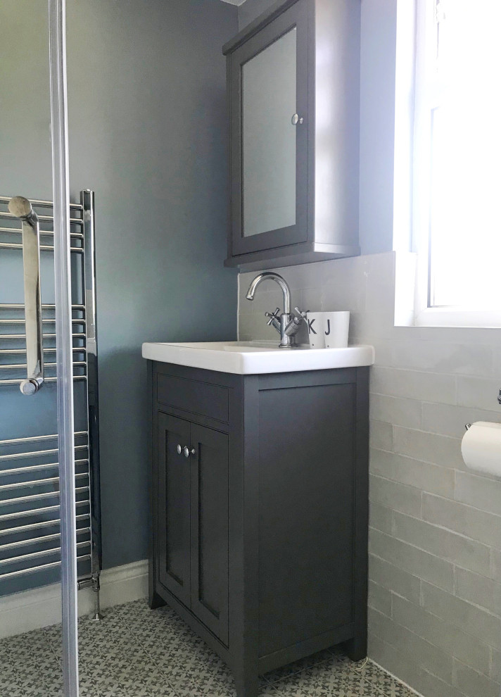 Bild på ett litet funkis en-suite badrum, med grå skåp, en hörndusch, en toalettstol med hel cisternkåpa, beige kakel, porslinskakel, blå väggar, klinkergolv i porslin, blått golv och dusch med skjutdörr