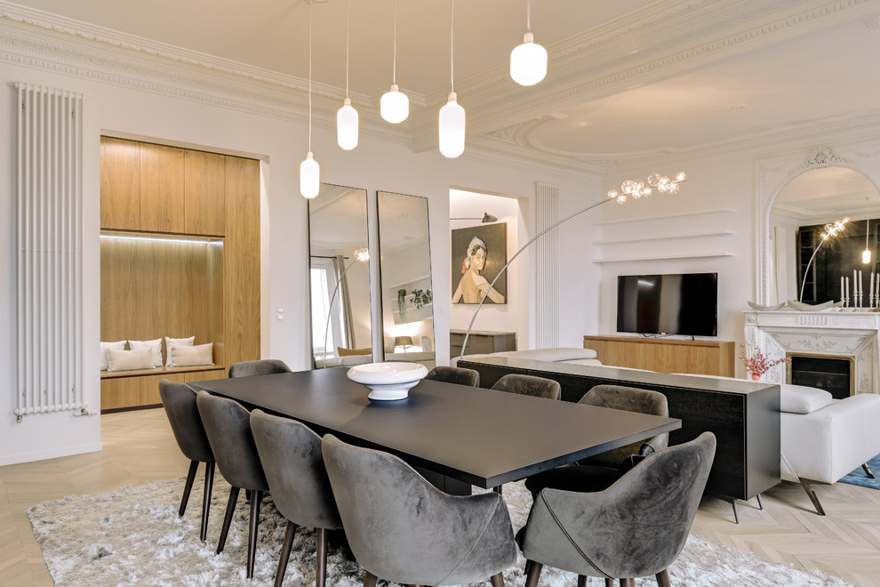 Contemporary dining room in Paris with white walls, light hardwood floors, a standard fireplace and beige floor.