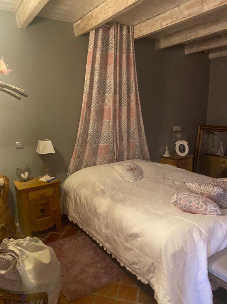 Imagen de dormitorio principal romántico de tamaño medio sin chimenea con paredes rosas, suelo de baldosas de terracota, suelo rojo y vigas vistas
