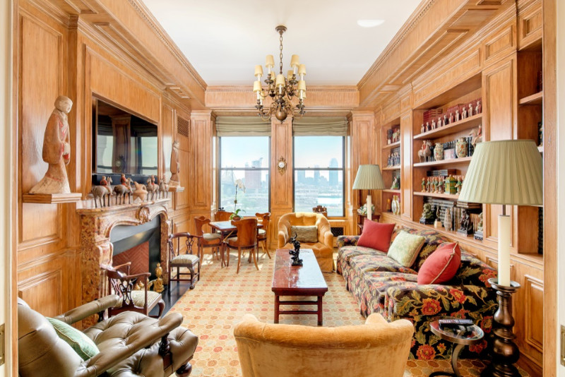 Photo of a large eclectic enclosed family room in New York with a library, beige walls, carpet, a standard fireplace, a stone fireplace surround and a wall-mounted tv.