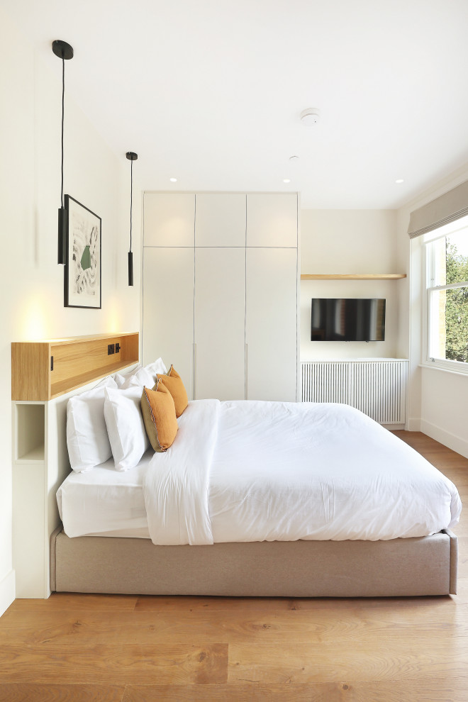 Immagine di una piccola camera da letto con parquet chiaro