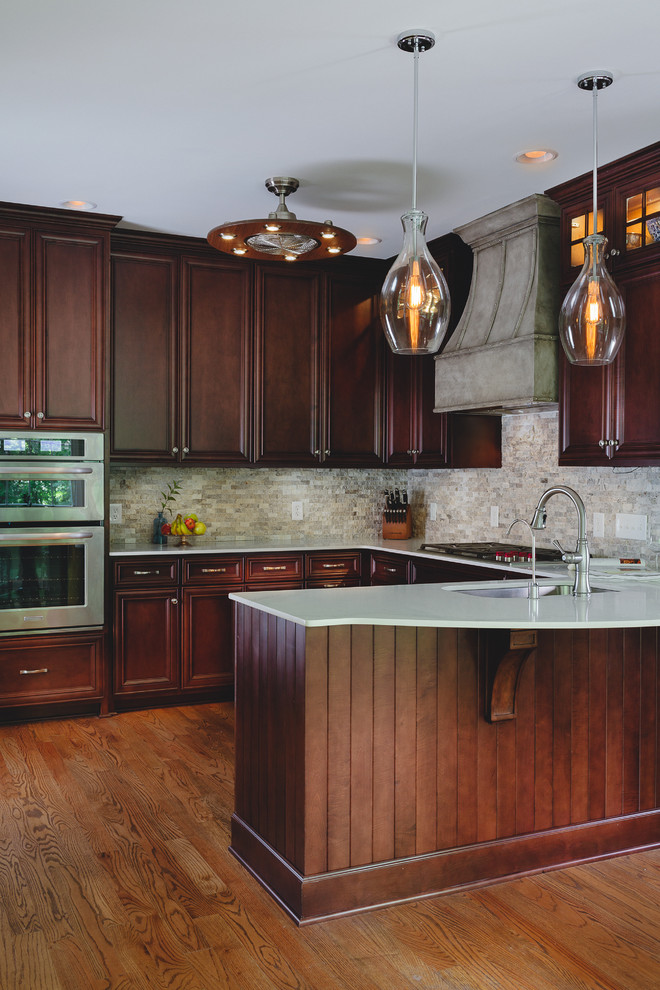 Inspiration for a large transitional u-shaped medium tone wood floor eat-in kitchen remodel in Atlanta with an undermount sink, raised-panel cabinets, dark wood cabinets, quartz countertops, gray backsplash, stone tile backsplash, stainless steel appliances and no island