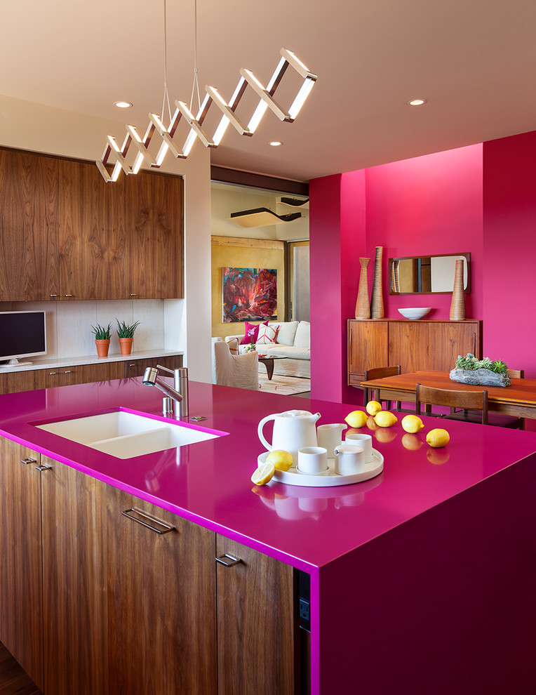 This is an example of a mid-sized contemporary u-shaped eat-in kitchen in Albuquerque with a double-bowl sink, flat-panel cabinets, medium wood cabinets, solid surface benchtops, white splashback, porcelain splashback, with island, stainless steel appliances and pink benchtop.