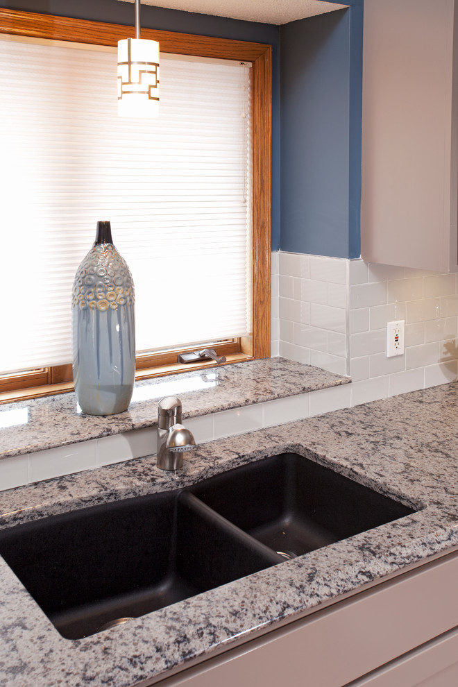 Mid-sized transitional l-shaped medium tone wood floor enclosed kitchen photo in Minneapolis with an undermount sink, recessed-panel cabinets, gray cabinets, quartz countertops, white backsplash, porcelain backsplash, stainless steel appliances, gray walls and an island