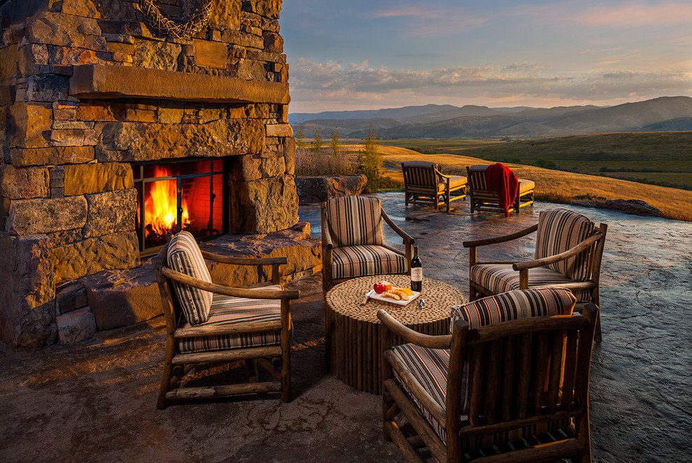 Huge mountain style backyard stamped concrete patio photo in Other with a fire pit and an awning