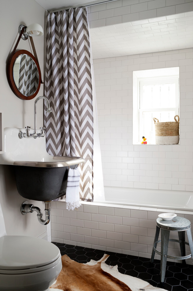 This is an example of a small transitional kids bathroom in DC Metro with a wall-mount sink, an alcove tub, a shower/bathtub combo, white tile, subway tile, white walls, ceramic floors, grey cabinets and a one-piece toilet.